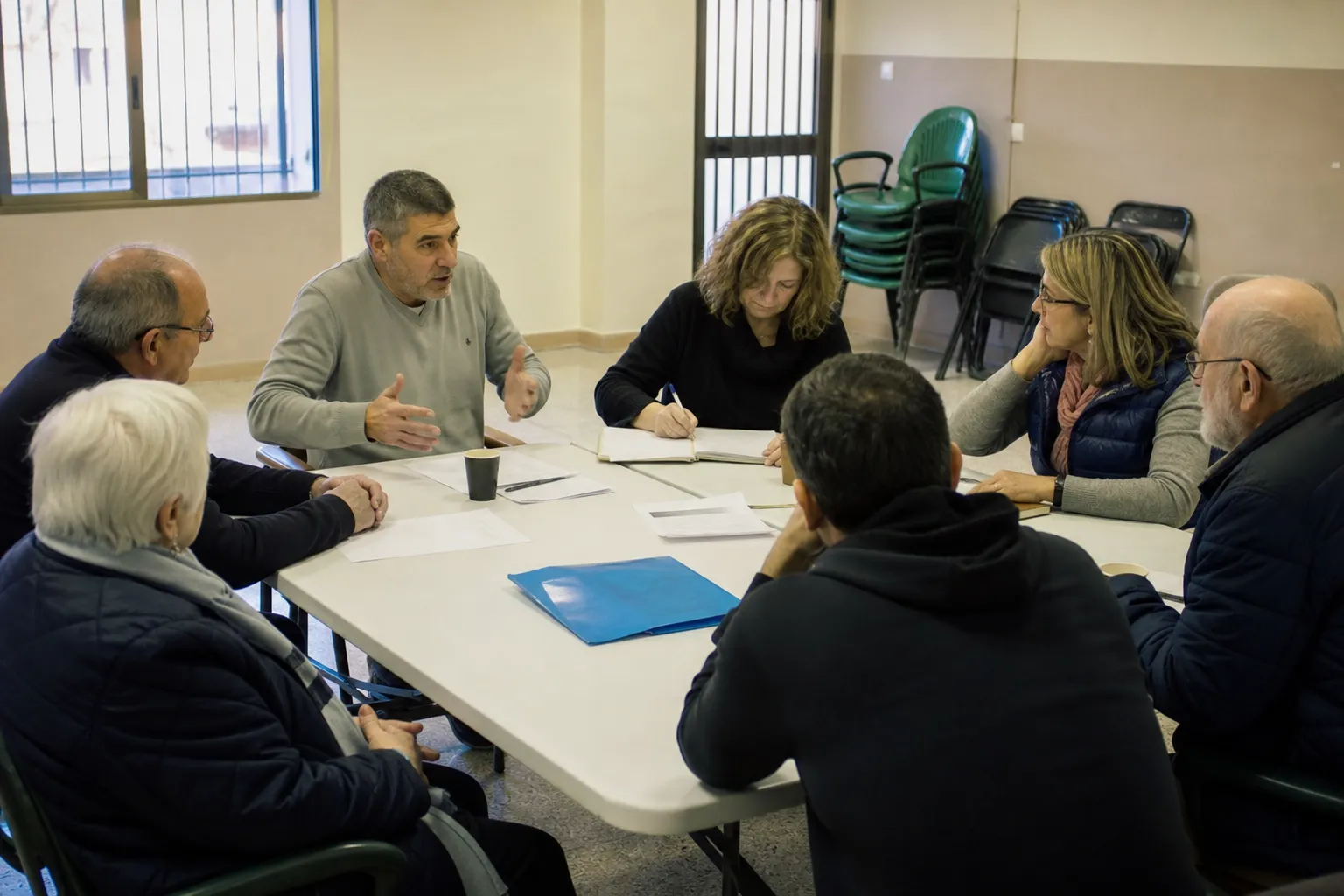 Junta de vecinos reunida con la documentación del salvaescaleras sobre la mesa