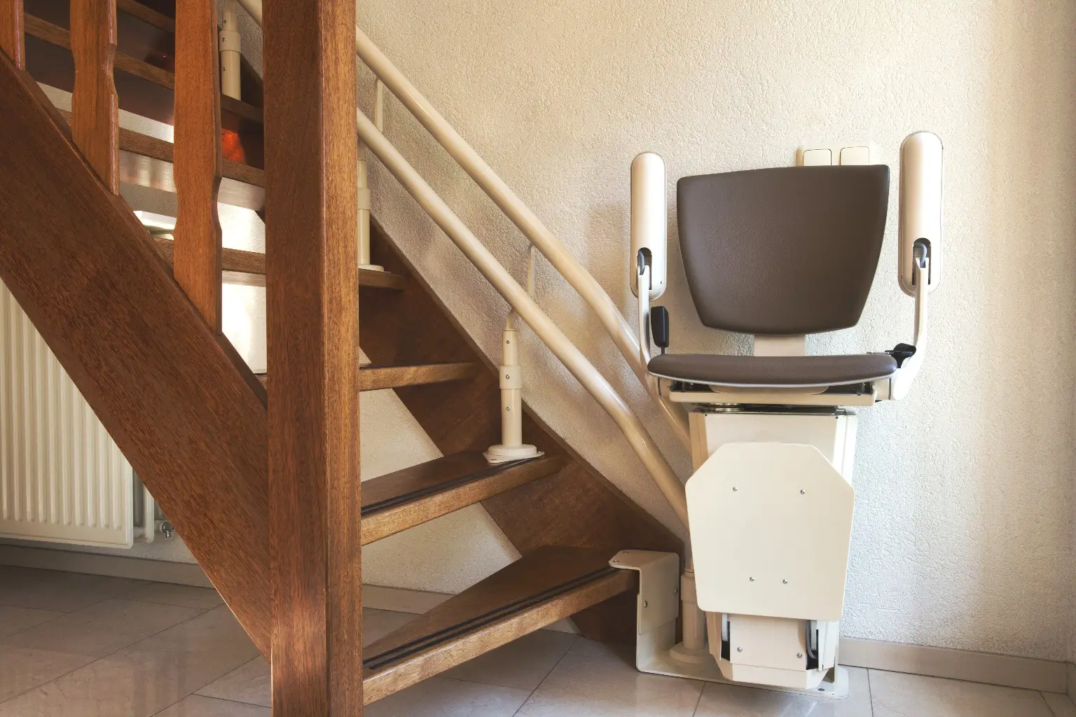Silla salvaescaleras plegada al pie de la escalera de madera de una vivienda de dos plantas